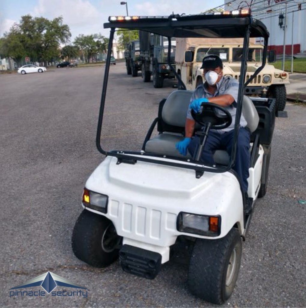 A Pinnacle Security officer wearing a protective mask while he drives a golf cart
