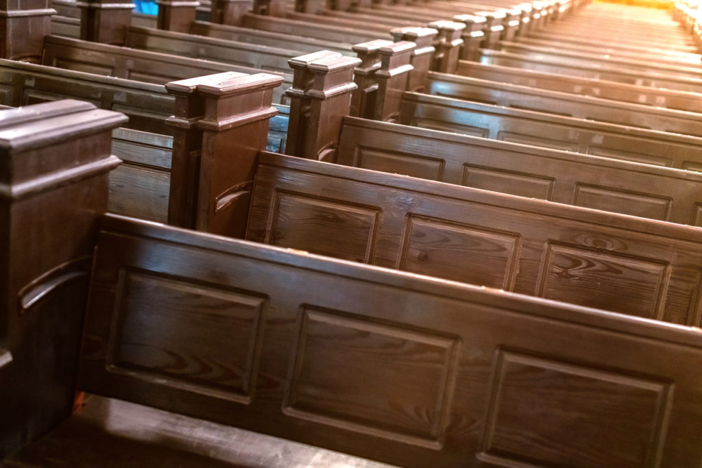 Cathedral benches. Rows of pews in christian church. Heavy solid uncomfortable wooden seats.